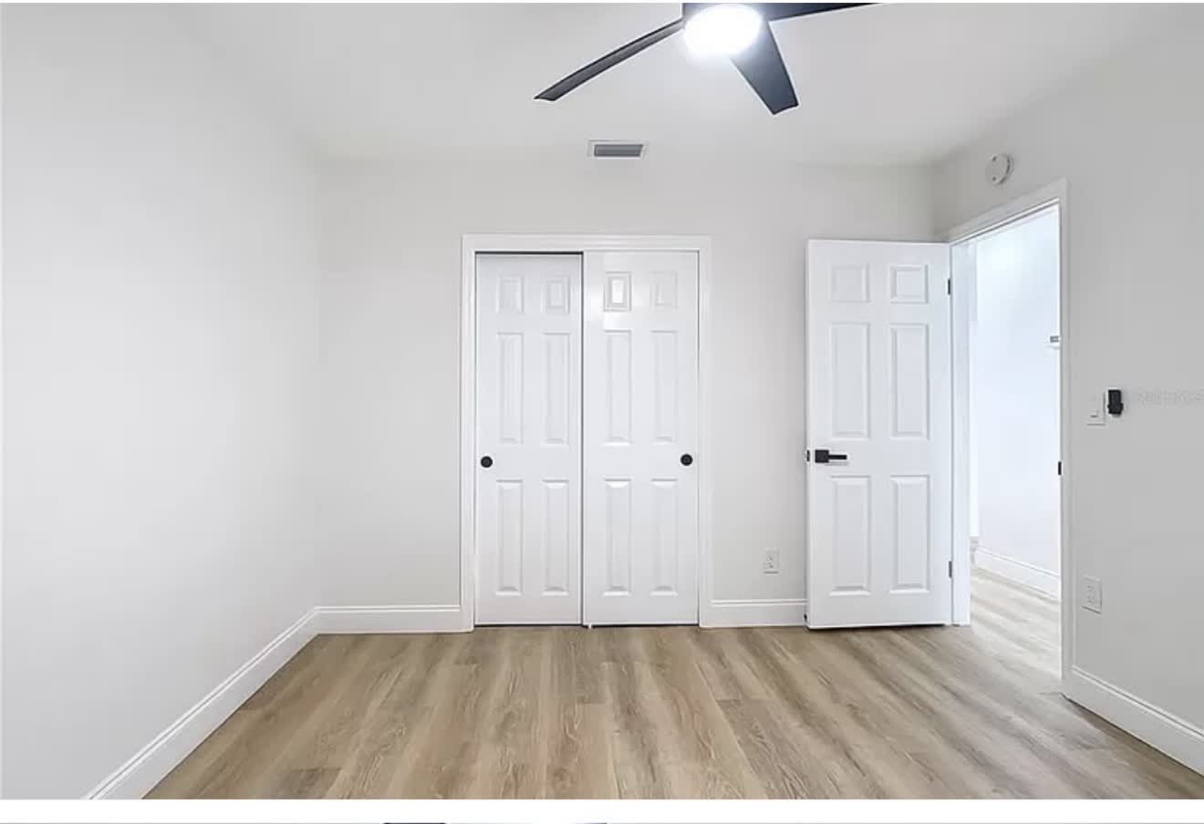Finished bedroom with smooth walls, fresh paint, and wood-look flooring
