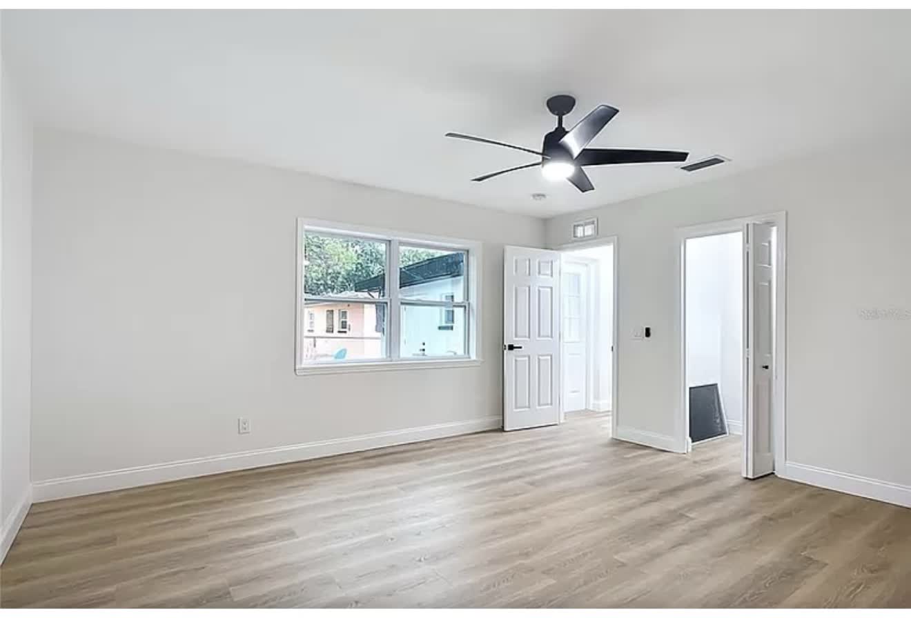 Remodeled bedroom with windows, wood-look flooring, and ceiling fan, second angle