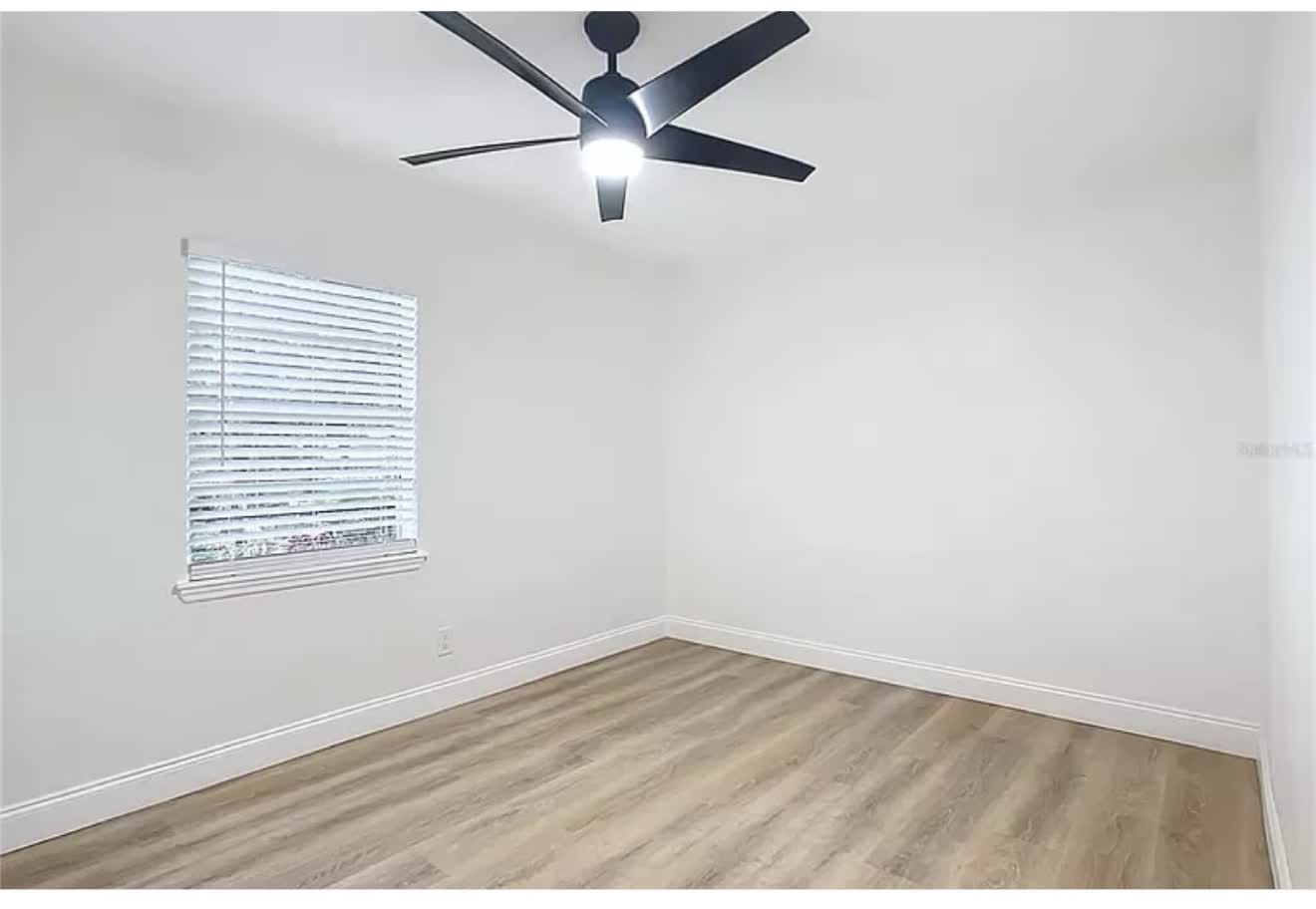 Remodeled bedroom with wood-look flooring and black ceiling fan