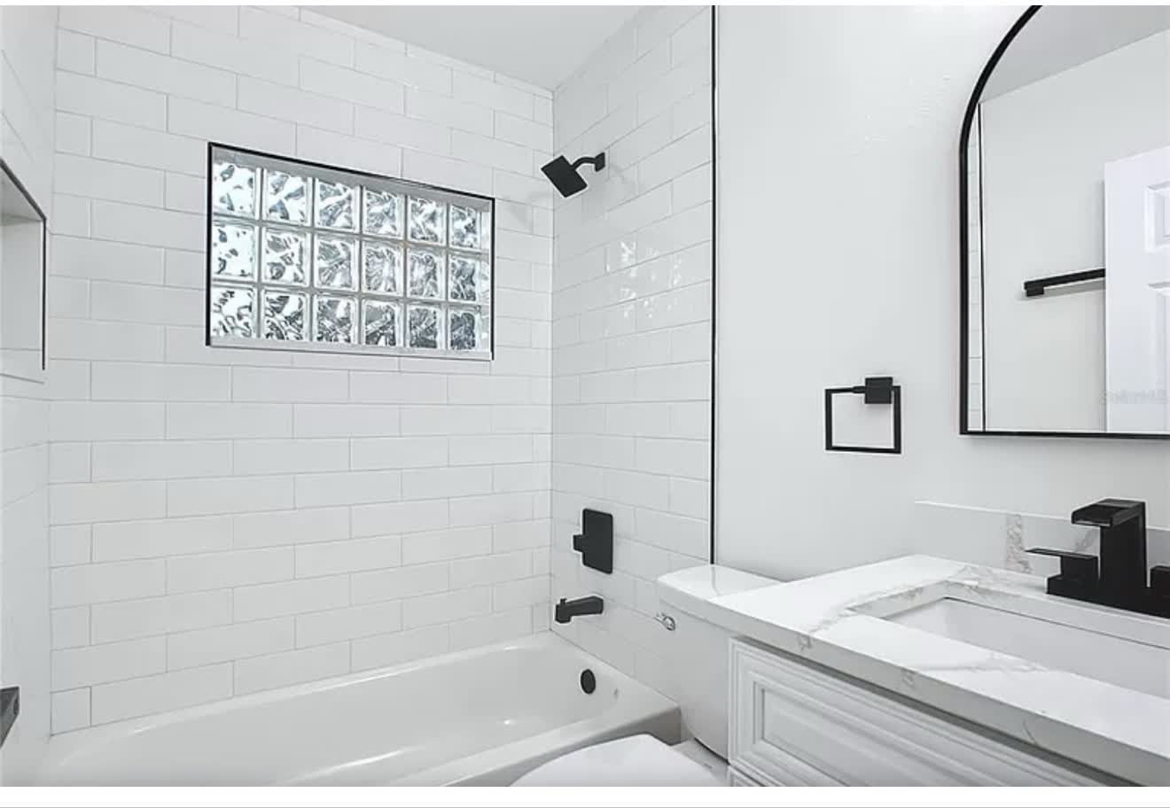Remodeled bathroom with white subway tile, vanity, and coordinated black fixtures