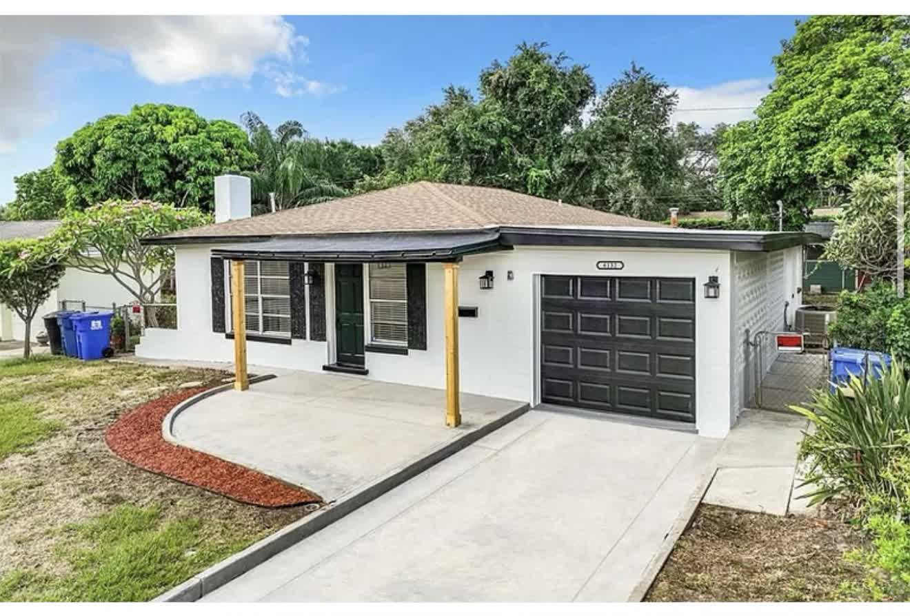 Remodeled house front exterior with white paint and black garage door, first angle