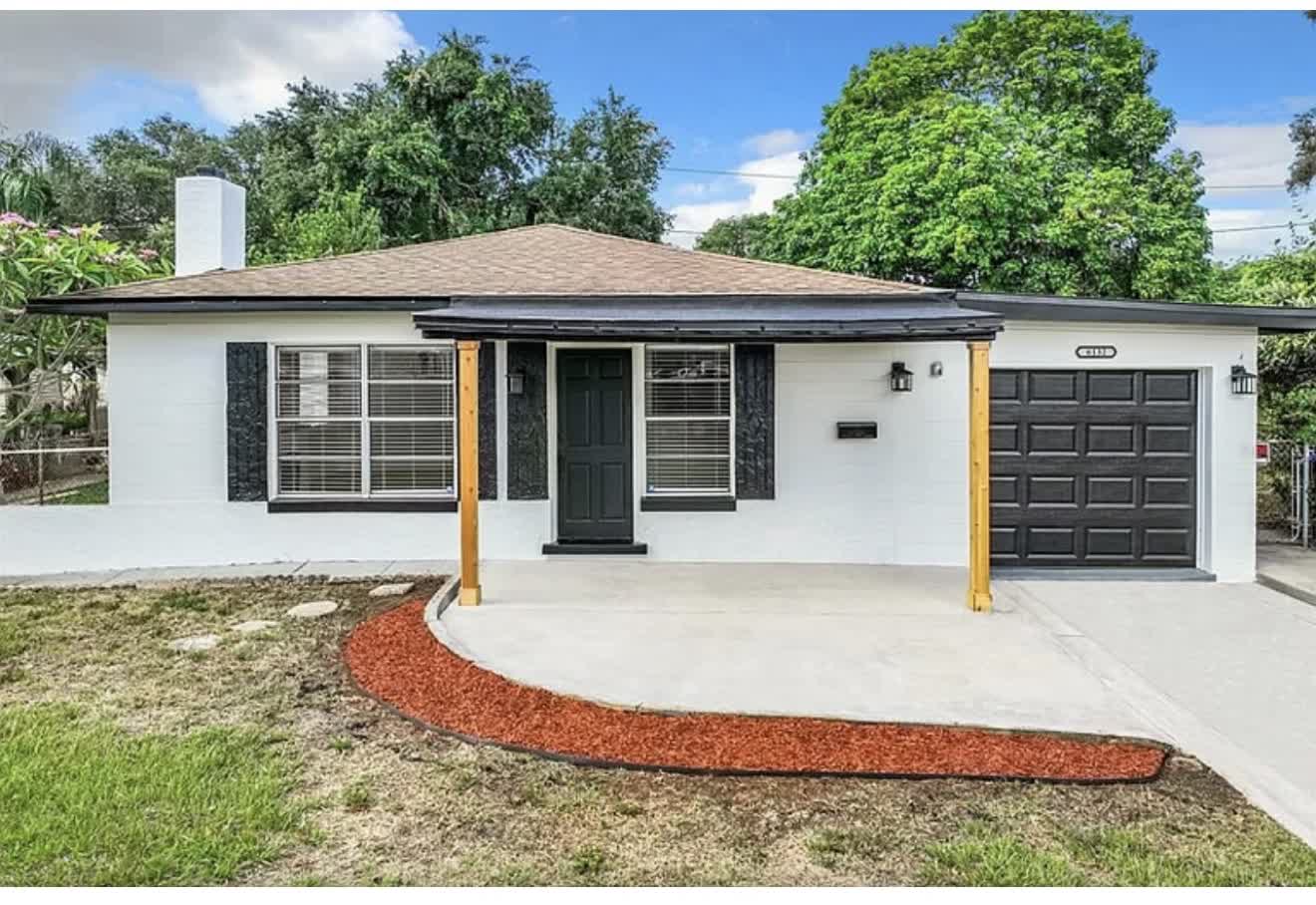 Remodeled house exterior from the side with white paint and fresh landscaping, second angle
